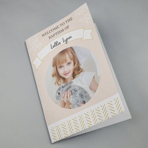 May include: A pink and white baptism invitation with a gold ribbon and the text "Welcome to the Baptism of Lollie Lynn". A photo of a young girl holding a rabbit is in the center of the invitation.