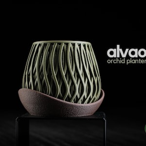 Peut inclure: Un cache-pot pour orchidée vert olive avec un motif de vagues verticales repose dans une soucoupe brun foncé texturée. Le texte alvao orchid planter est imprimé en blanc à droite, et un petit logo circulaire vert h3liø design est en bas.