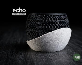 May include: Black and white Echo orchid planter with a unique wave pattern design. The planter sits on a textured, white base. The words "echo orchid planter" are printed on the top left.