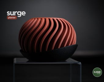 May include: A terracotta-coloured, spherical planter with a unique, wave-like design. The planter sits on a black, textured base. The word "surge" and "planter" are displayed in white and brown text.