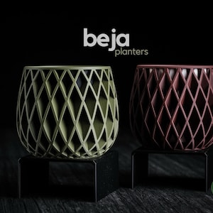 Può includere: Due fioriere decorative con intagli a forma di diamante. Una è verde oliva, l'altra è marrone. Entrambe sono su supporti neri su sfondo nero. La parola "beja planters" è sopra.