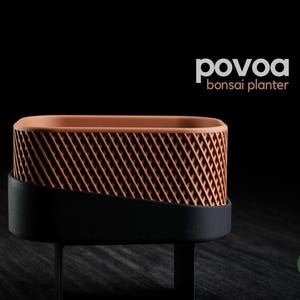 Op de afbeelding: Een rechthoekige bonsai-plantenbak met een terracotta-kleurig bovendeel met een diagonaal roosterpatroon en een effen zwarte onderkant. De tekst "povoa bonsai planter" staat rechtsboven en een groen "h3liø design"-logo staat rechtsonder.