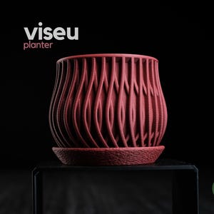Op de afbeelding: Een donkerrode plantenbak met een getextureerd, verticaal golfpatroon en een bijpassende schotel. De tekst "viseu planter" staat in wit en lichtrood boven het object en een groen "h3liø design"-logo is rechtsonder zichtbaar.