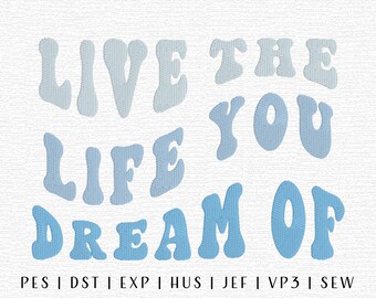 May include: Light and medium blue text on a white background reads "LIVE THE LIFE YOU DREAM OF" in a retro font. Below the text are embroidery file format abbreviations.