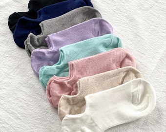 May include: A set of nine pairs of no-show socks in various colors, including white, beige, pink, light pink, light blue, lavender, gray, navy blue, and black.