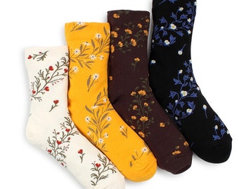 May include: Four pairs of socks with floral patterns. The socks are in white, yellow, brown, and black with different floral designs.