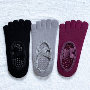 Könnte beinhalten: Drei Paar Zehensocken in Schwarz, Grau und Burgunderrot. Jede Socke hat ein separates Fach für jeden Zeh und einen rutschfesten Griff an der Sohle. Die Socken sind für Aktivitäten wie Yoga und Pilates konzipiert.