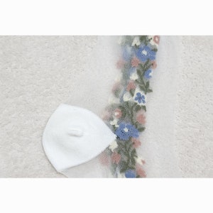 May include: White sheer socks with a floral design in blue, pink, and green. The floral design is on the side of the socks.