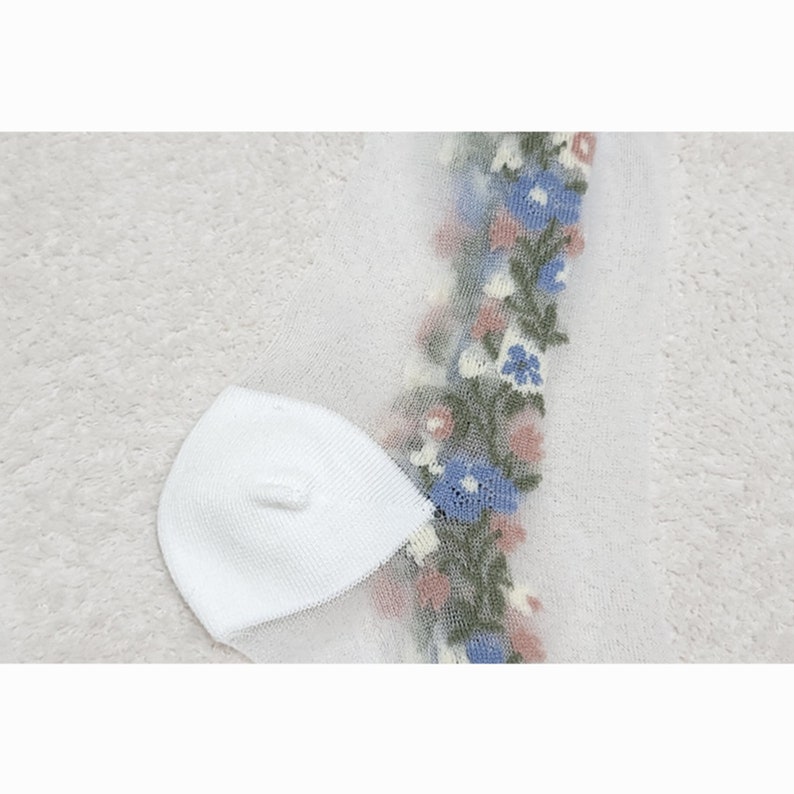 May include: White sheer socks with a floral design in blue, pink, and green. The floral design is on the side of the socks.
