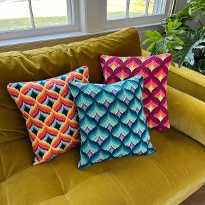 Può includere: Quattro cuscini decorativi con motivi geometrici nei toni dell'arancione, del blu e del rosso poggiano su un divano in velluto giallo senape. I cuscini presentano disegni intricati, aggiungendo colore e consistenza all'arredamento della stanza.