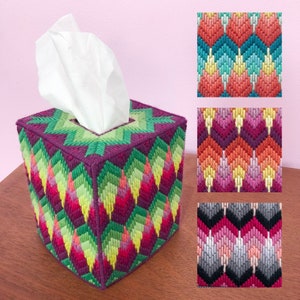 May include: A purple tissue box cover with a geometric pattern in shades of green, yellow, pink, and red. The pattern is made up of small diamonds and triangles.