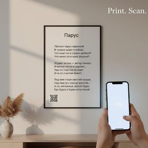 May include: A framed print with a black border displays a poem in Russian. The text "Print. Scan. Listen." is at the top right. A smartphone with a white screen is held in front of the print, and a vase with dried flowers sits on a wooden surface.