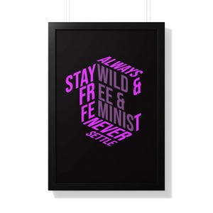 Può includere: Stampa artistica con cornice nera con le parole "Stay Wild Free & Feminist Never Settle" in un carattere viola in stile 3D. La stampa artistica è appesa a una parete bianca.