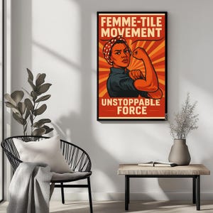 Può includere: Un poster incorniciato con il testo "FEMME-TILE MOVEMENT" e "UNSTOPPABLE FORCE". L'immagine presenta una donna che flette il braccio, con una bandana a pois rossi e bianchi, su uno sfondo a raggi rossi e arancioni.