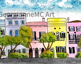 May include: Watercolor painting of colorful buildings with trees and a blue sky. The buildings are painted in shades of blue, pink, and yellow. The artwork is signed by the artist, GeorgianneMC Art.