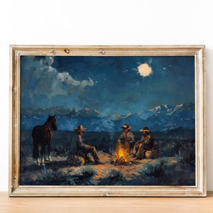 May include: A framed painting depicting a nighttime scene with four cowboys gathered around a campfire under a full moon. The cowboys are wearing hats and sitting on the ground. A horse stands behind them. The painting is set against a backdrop of mountains and a starry sky.