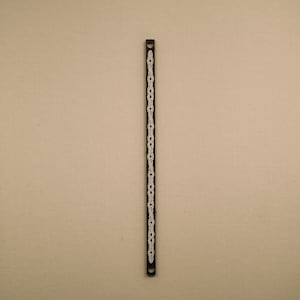 以下が含まれることがあります： 白いチェーンのデザインが施された黒い金属製のブレスレット