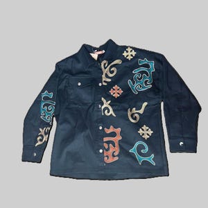 Pode incluir: Uma camisa azul marinho escuro com botões e mangas compridas. A camisa apresenta patches bordados decorativos em verde-azulado, dourado, vermelho e branco. Os patches têm um design único e estilizado. A camisa tem um bolso no peito.