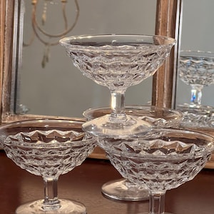 Könnte beinhalten: Vier klare Champagnerkelche aus Glas mit Diamantmuster. Die Kelche sind übereinander gestapelt.