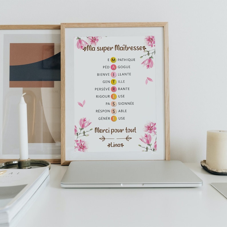 Op de afbeelding: Een ingelijst afdruk met een roze bloemenontwerp en de tekst "Ma super Ma&icirc;tresses" en "Merci pour tout" met de naam "Linas" onderaan. De afdruk bevat een woordpuzzel met de letters "E M A T I R S" en de woorden "PATHIQUE, GOGUE, ILLANTE, TILLE, RANTE, EUSE, SIONN&Eacute;E, SABLE, USE".