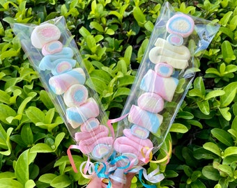 May include: Two clear plastic bags filled with colorful marshmallows on sticks, tied together with colorful ribbons.