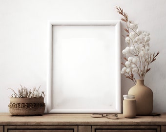 May include: A white picture frame with a blank canvas sits on a wooden dresser with two drawers. A vase with dried white flowers and a glass jar are on the dresser.