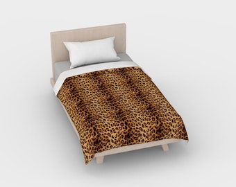 Puede incluir: Una cama individual con un edredón de estampado de leopardo marrón y negro y una almohada blanca. El marco de la cama es de madera y tiene un acabado marrón claro.