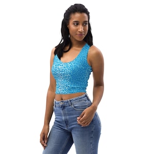 May include: A blue leopard print crop top with a scoop neckline. The sleeveless top is worn with blue jeans. The top is made of a soft material. The model is wearing blue jeans.