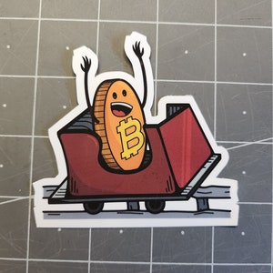 May include: A cartoon illustration of a gold Bitcoin coin with a smiling face riding a red roller coaster. The coin has the Bitcoin symbol "B" in the center.