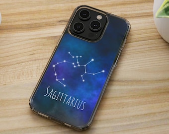 May include: A clear phone case featuring a blue and purple galaxy design with the Sagittarius constellation in white. The word "SAGITTARIUS" is printed in white below the constellation. The phone case is on a wooden surface.