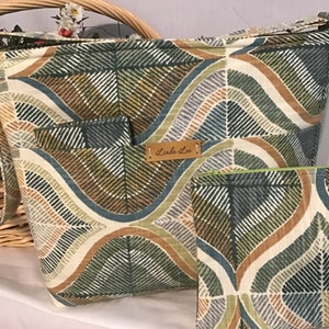 May include: A large, beige tote bag with a green, brown, and blue geometric pattern. The bag has a long strap and a smaller matching zippered pouch. The bag has a leather tag that says "Linda Lee".