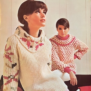 May include: Two women wearing knitted sweaters. The woman on the left is wearing a white sweater with a pink, green, and brown floral design on the collar and sleeve. The woman on the right is wearing a pink sweater with white polka dots.