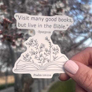 May include: A white sticker with the quote "Visit many good books, but live in the Bible." by Spurgeon. The sticker features an open book design with floral illustrations and the text "Psalm 119:114".