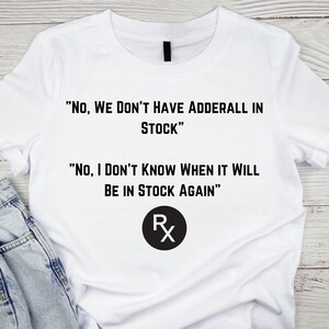 May include: White t-shirt with black text that reads "NO, WE DON'T HAVE ADDERALL IN STOCK" and "NO, I DON'T KNOW WHEN IT WILL BE IN STOCK AGAIN". A black circle with the letters RX is below the text.