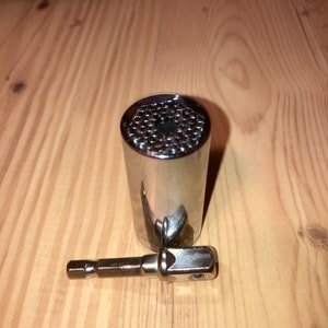 May include: A silver socket wrench with a variety of sizes for different nuts and bolts. The wrench has a hexagonal shape and a black handle.