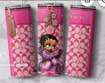 May include: Pink tumbler with a repeating pattern of interlocking Cs and a pink leather-like top and bottom. The tumbler features a cartoon image of Betty Boop holding a phone. A charm with flowers and a Coach tag hangs from the top.