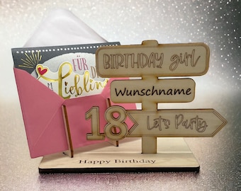 Peut inclure: Une pancarte d'anniversaire en bois avec une enveloppe rose et une carte. La pancarte a trois flèches en bois avec le texte "Birthday girl", "Wunschname" et "Let's Party". Le numéro 18 est également sur la pancarte. La pancarte indique "Happy Birthday" en bas.