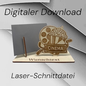 Könnte beinhalten: Ein lasergeschnittenes Holzdesign mit einer Filmrolle, einem Popcorn-Eimer und dem Wort "CINEMA". Das Design befindet sich auf einer Holzbasis mit dem Wort "Wunschtext" darunter. Das Design ist für einen digitalen Download.