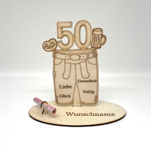 Könnte beinhalten: Holzkarte zum 50. Geburtstag mit einer Hose, einem Bierkrug, einem Brezel und den Worten "Liebe", "Glück", "Gesundheit", "Erfolg" und "Wunschname".