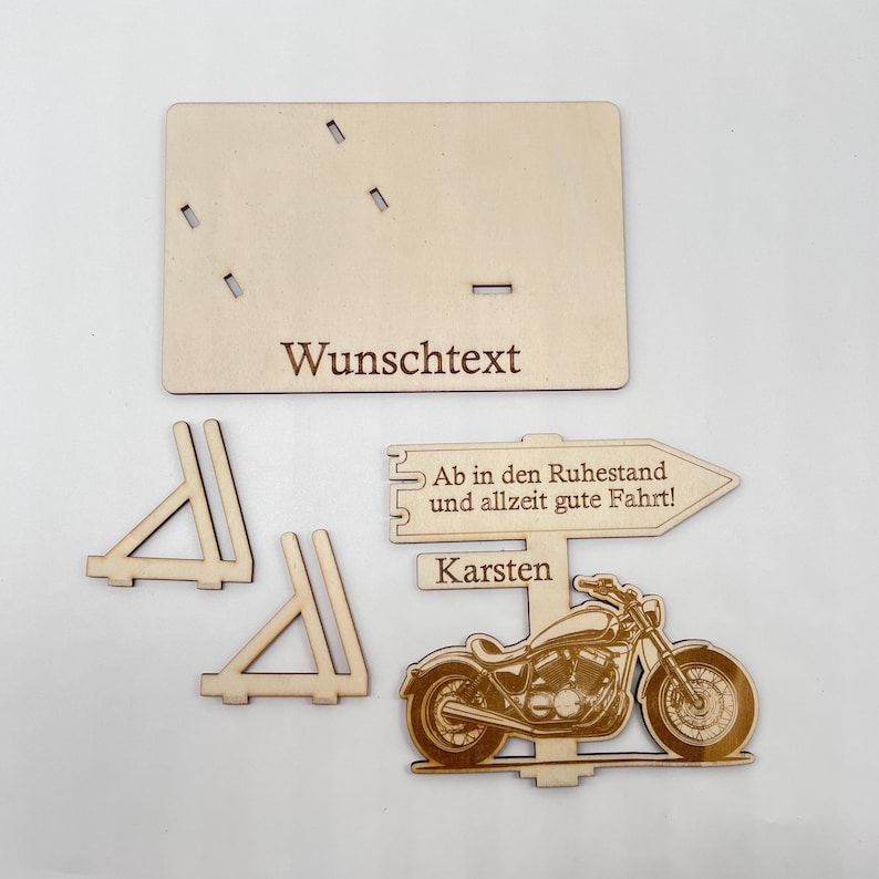 May include: Wooden motorcycle retirement sign with a personalized message, a sign that reads "Ab in den Ruhestand und allzeit gute Fahrt!" and the name "Karsten".