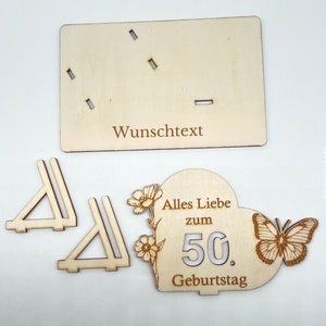 May include: Wooden craft kit for a 50th birthday. The kit includes a heart-shaped plaque with the text "Alles Liebe zum 50. Geburtstag" and a butterfly, two wooden stands, and a blank plaque for a personalized message.