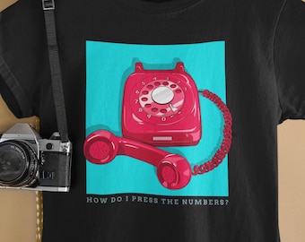 May include: Black t-shirt with a red rotary phone graphic and the text "How do I press the numbers?" printed on the front.