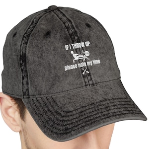 May include: A dark grey baseball cap with a curved peak. The cap has white text that reads "IF I THROW UP please note my time" with a rowing graphic and crossed oars.