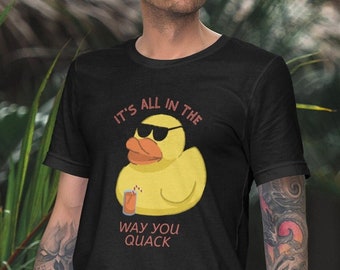 May include: Black t-shirt featuring a yellow rubber duck wearing sunglasses and holding a glass of orange juice. The text on the shirt reads "It's all in the way you quack."