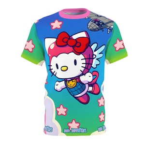 May include: A vibrant t-shirt with a cartoon character design, including a red bow and wings, set against a blue sky with stars and a spaceship. The shirt has a pink collar and green sleeves. The text "DAK INDUSTRIES" is visible.