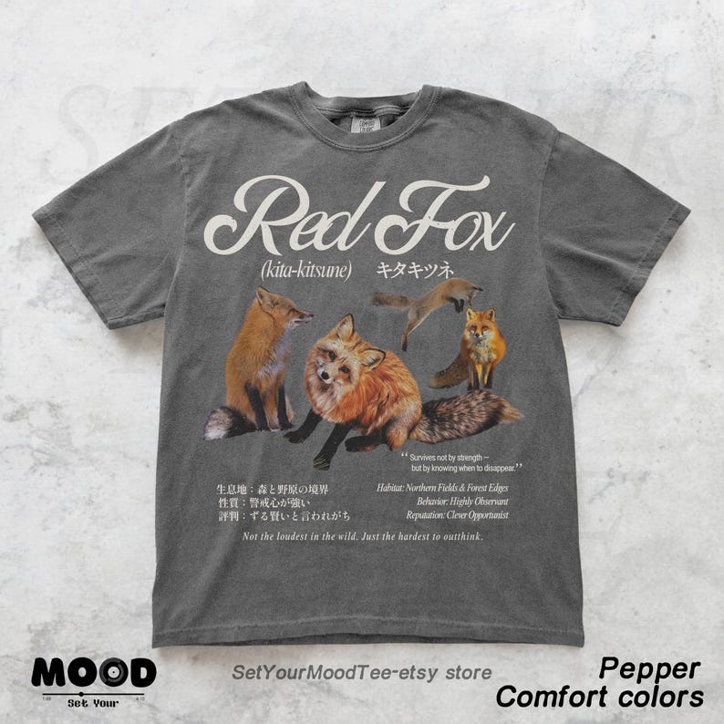 K&ouml;nnte beinhalten: Graues T-Shirt mit einem Aufdruck von Rotf&uuml;chsen und dem Text "Red Fox" in Englisch und Japanisch. Der Entwurf enth&auml;lt den Satz "Not the loudest in the wild. Just the hardest to outthink." Teil der "Comfort colors"-Kollektion.