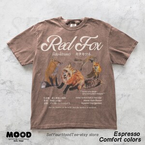 K&ouml;nnte beinhalten: Espressofarbenes T-Shirt mit einer Grafik von Rotf&uuml;chsen und dem Text "Red Fox" dar&uuml;ber. Das Shirt enth&auml;lt japanischen Text und zus&auml;tzlichen Text &uuml;ber den Lebensraum und das Verhalten des Fuchses. Teil der "Comfort Colors"-Kollektion.