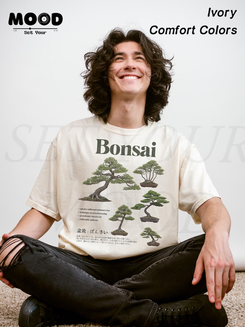 May include: Ivory-colored t-shirt with a Bonsai tree graphic. The shirt features several illustrations of Bonsai trees, along with text in English and Japanese. The shirt also has the text "Comfort Colors" and the word "Ivory" printed on it.