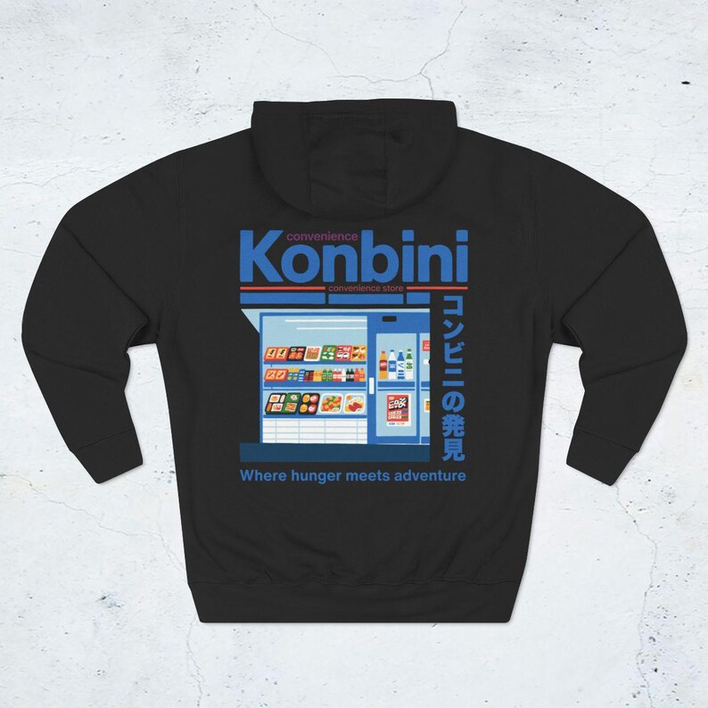 May include: Black hoodie featuring a graphic of a convenience store with the word "Konbini" in blue and Japanese text. The phrase "Where hunger meets adventure" is printed below the store illustration.