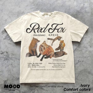 K&ouml;nnte beinhalten: Elfenbeinfarbenes T-Shirt mit einer Grafik von Rotf&uuml;chsen und dem Text "Red Fox" und "(kita-kitsune)". Das Design enth&auml;lt Text, der den Lebensraum und das Verhalten des Fuchses beschreibt. Das T-Shirt ist Teil der "Comfort colors"-Kollektion.